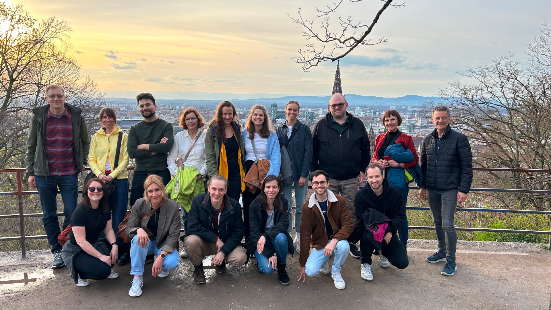 Ein Gruppenfoto des SHUFFLE-Teams auf einer Anhöhe in Freiburg. Im Hintergrund sieht man einen Sonnenuntergang sowie ein Teil der Stadt.